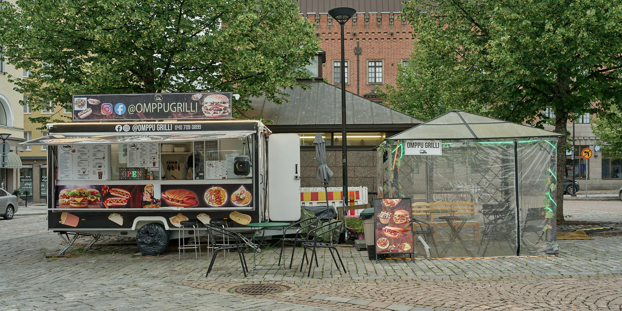 Imbisswagen mit leeren Tischen und Stühlen auf einem gepflasterten Platz
