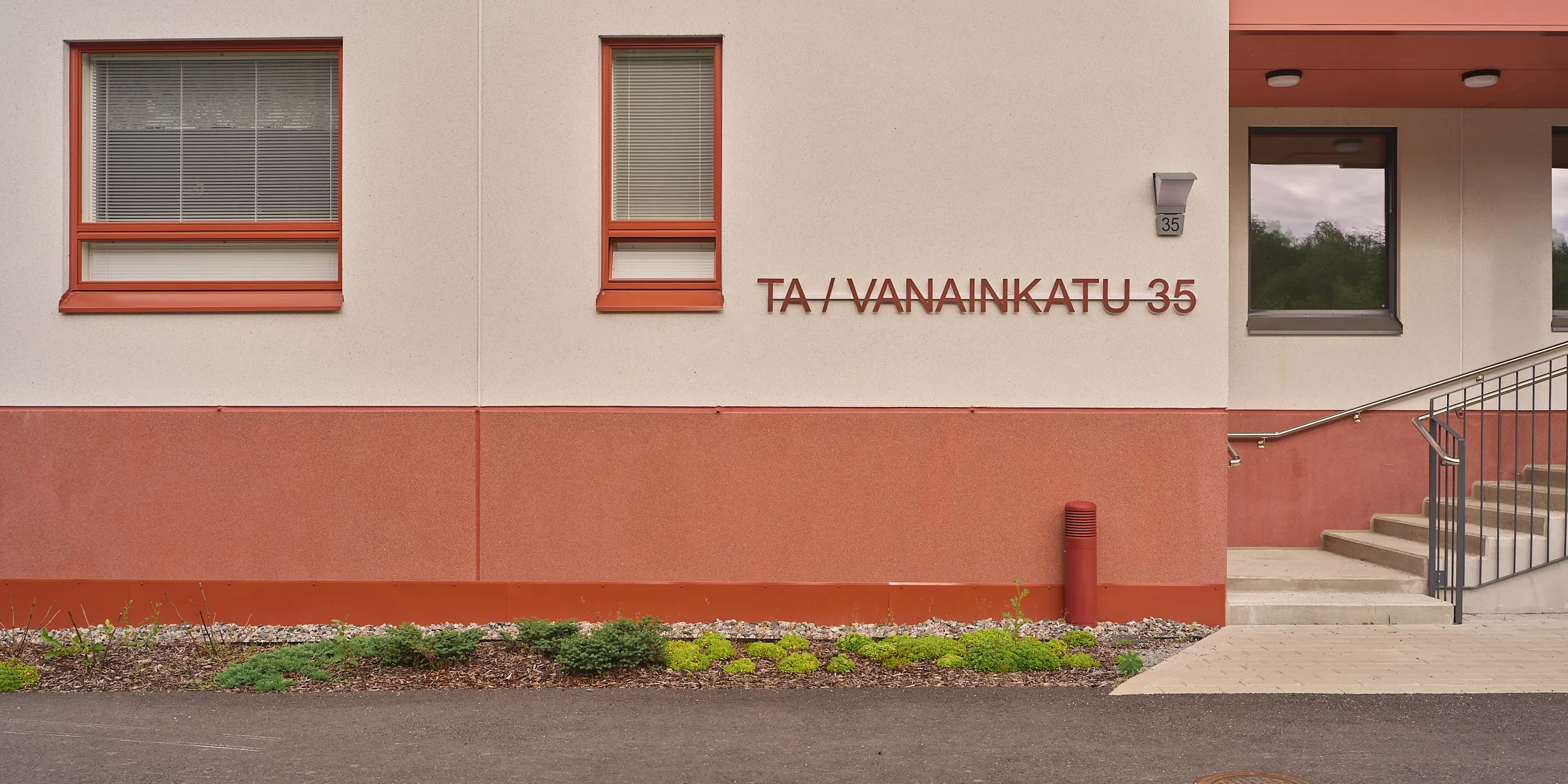 Rotbraun abgesetzte Wohnhausfassade mit dem Schriftzug Vanainkatu 35