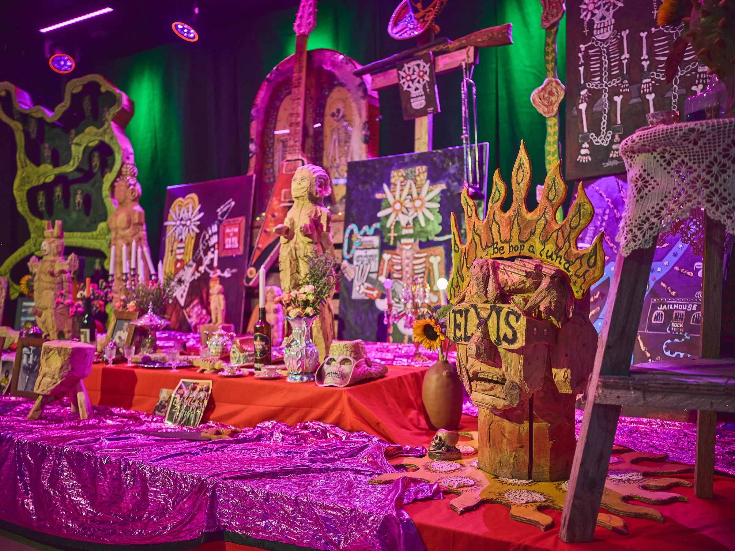 Altar mit geschnitzten Flammen, Sonnenblumen und gerahmten Bildern auf rotem Tuch