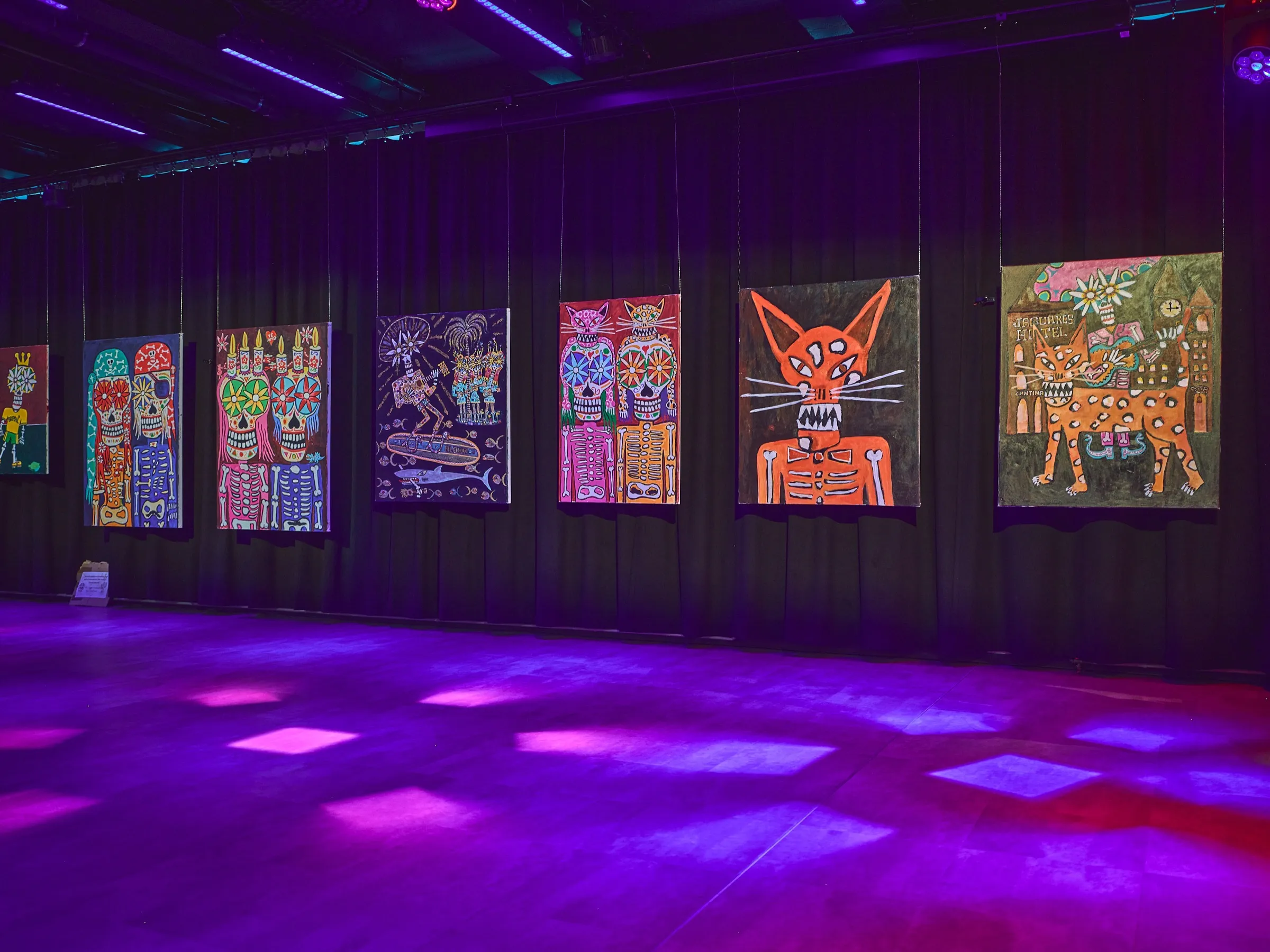 Lange Wand mit bunten Bildern in einem dunklen Raum, gemustertes Licht auf dem Boden