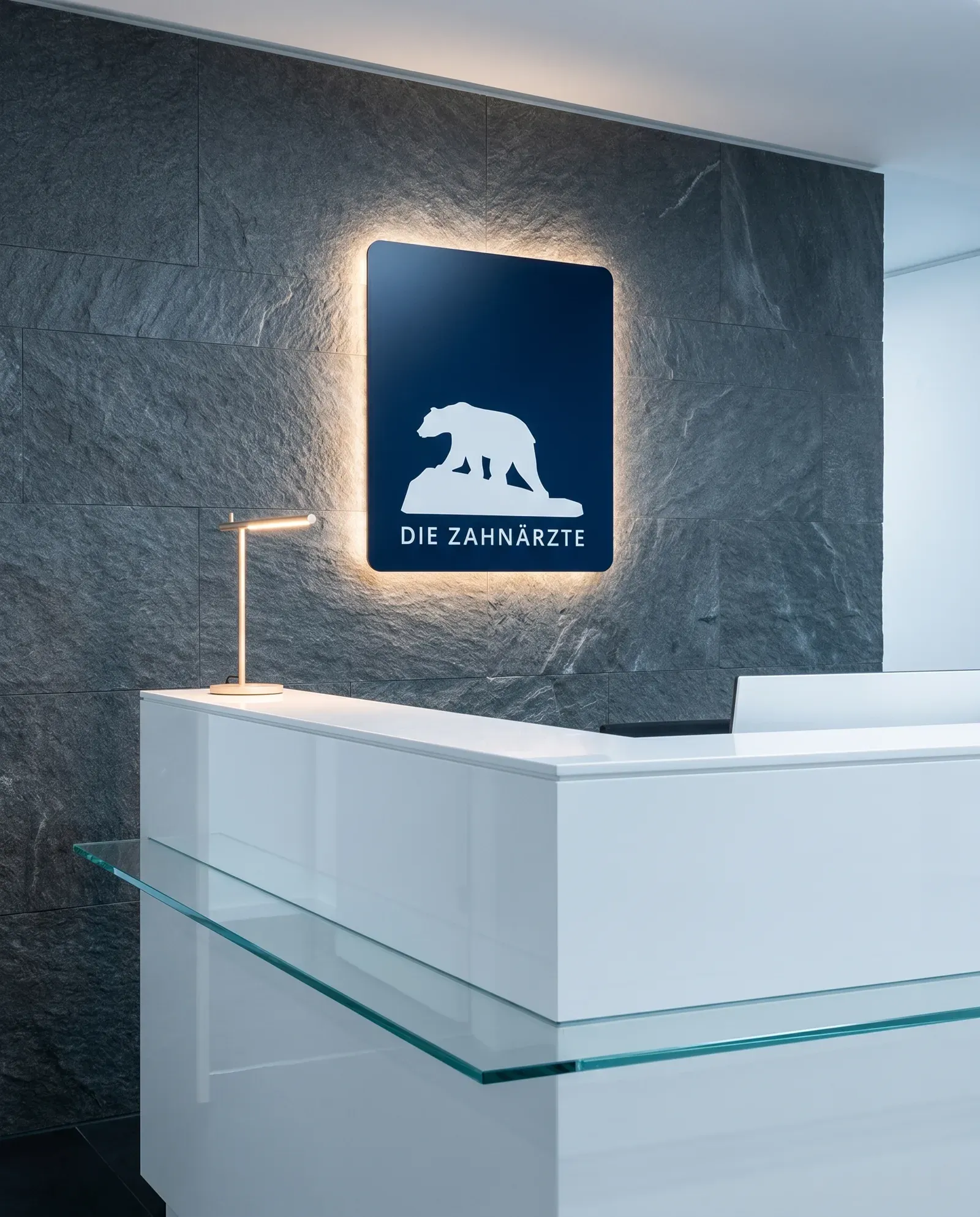Beleuchtetes Logo Die Zahnärzte an der Empfangswand einer Praxis, weißer Eisbär auf dunkelblauem Grund