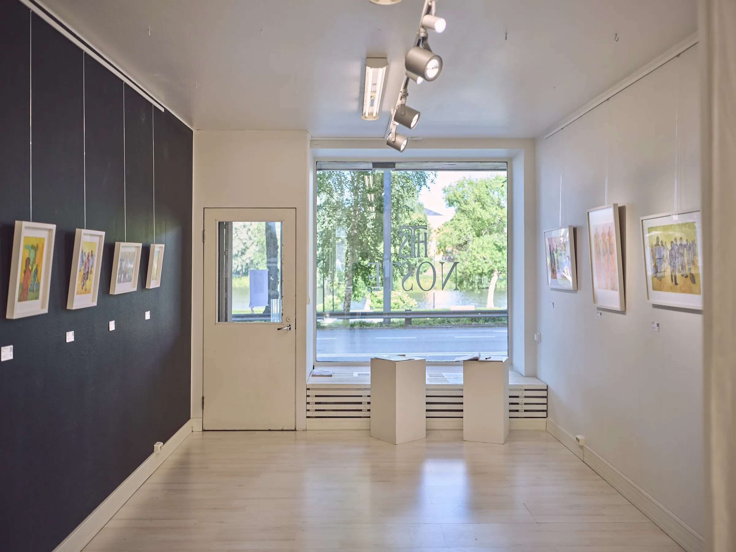 Galerieraum mit dunkler und heller Wand, in der Mitte das große Fenster zur Straße