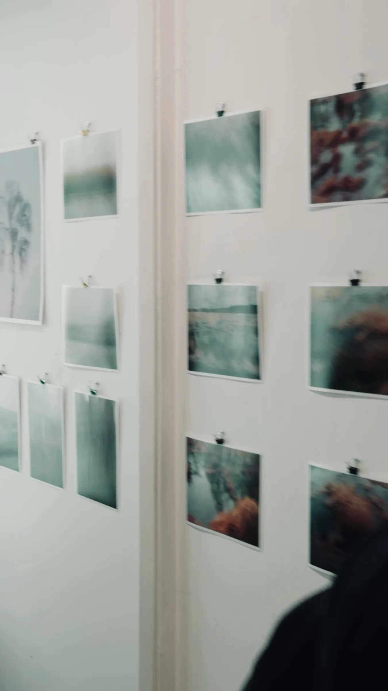 Kurzes Video: Fotografien liegen sortiert auf einem weißen Tisch, dann der Blick auf die fertig gehängte Wand
