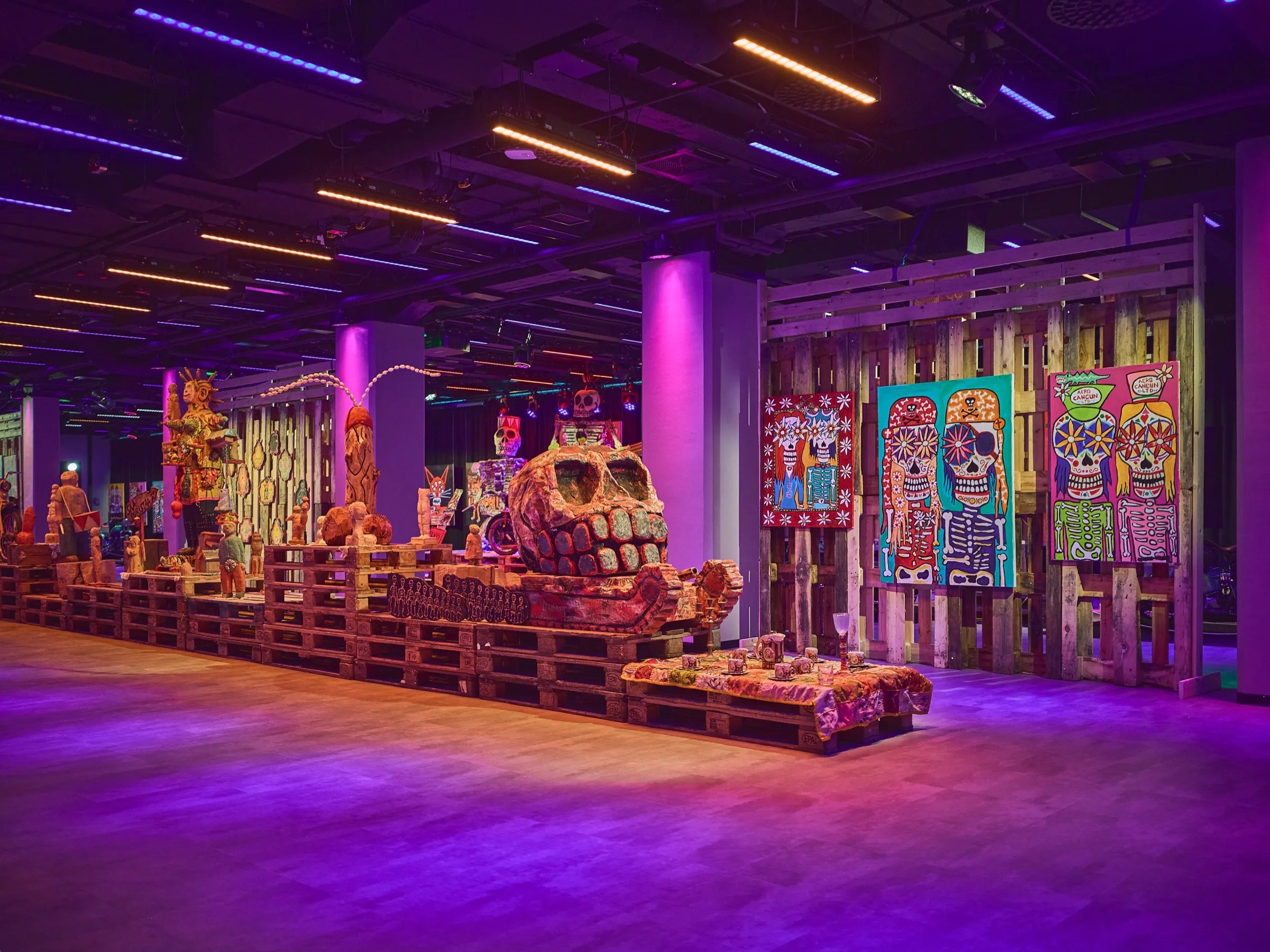 Blick in den dunklen Ausstellungssaal Verki mit Skulpturen, Bildern und violettem Licht