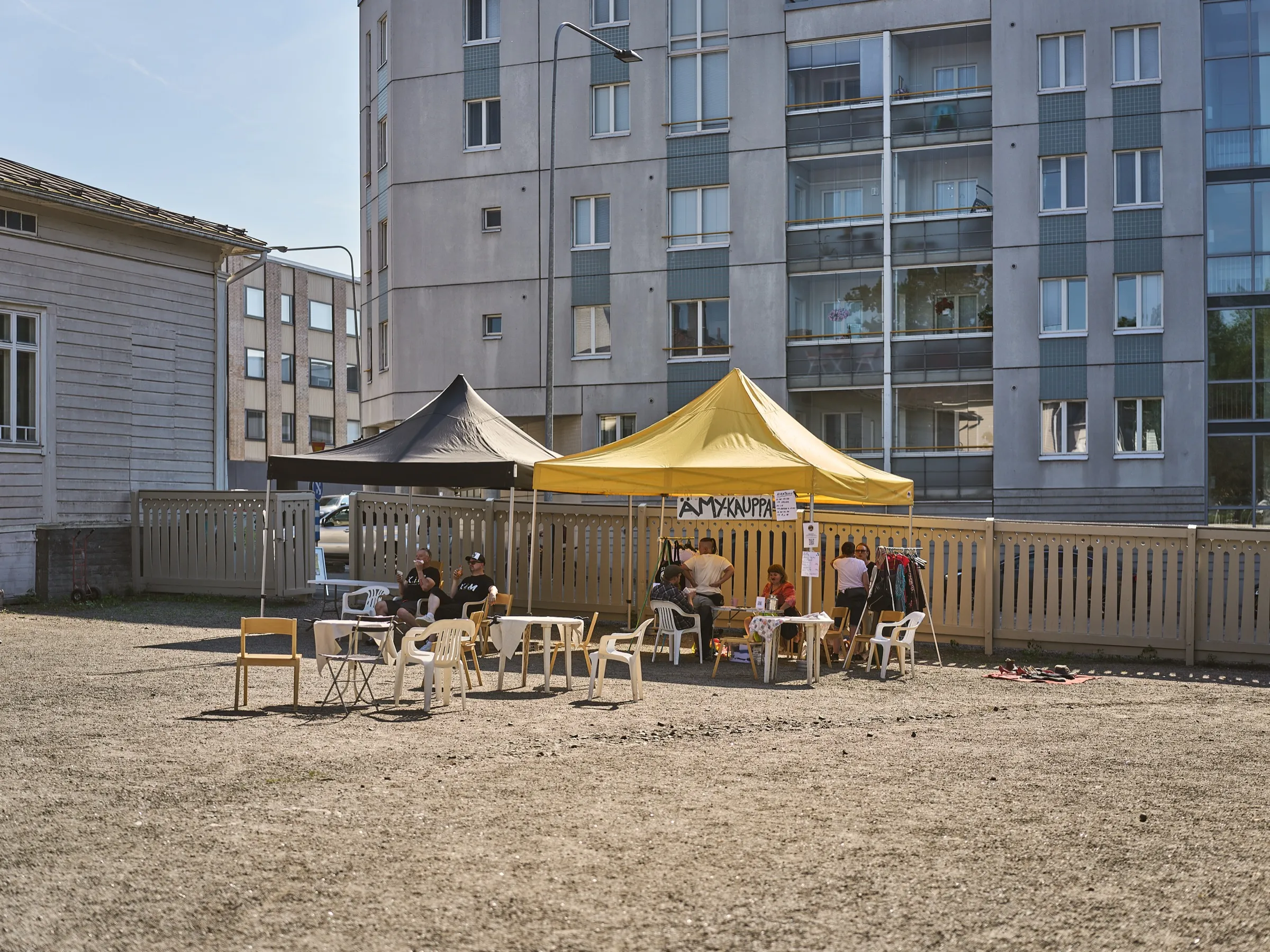 Innenhof beim Ämykesä mit Zelten, Flohmarktständen und einem Wohnhaus im Hintergrund