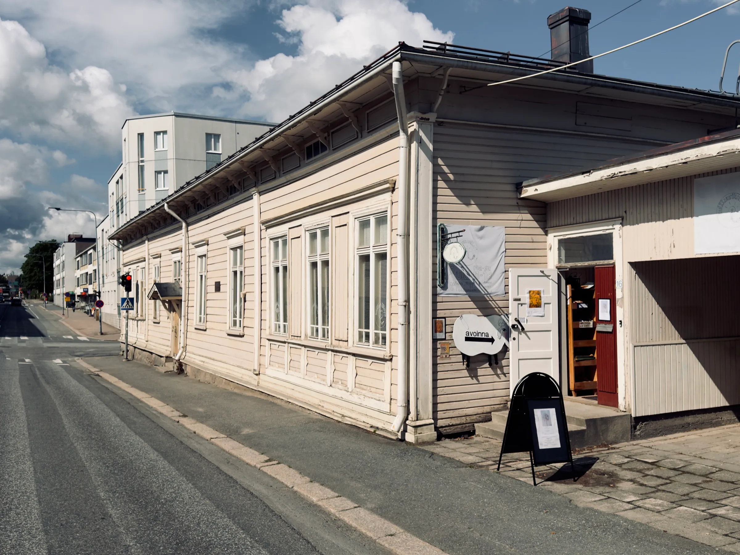 Das alte Holzhaus des Kulttuurikonttori in Hämeenlinna, davor Bäume und Sommerlicht
