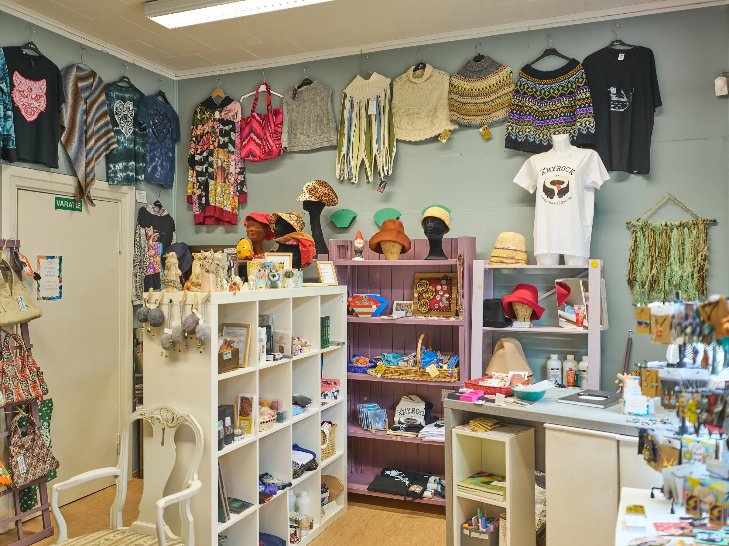 Der kleine Laden mit handgemachtem Design: Strickteile und Shirts an der Wand, Hüte, Keramik und Regale voller Kleinigkeiten
