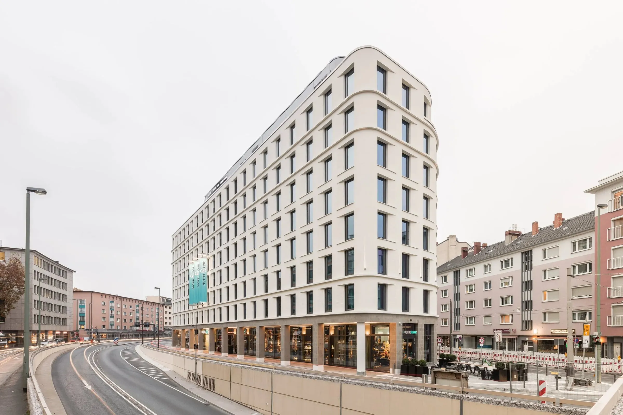Außenansicht des Motel One in Frankfurt von KSP Engel, weiße gerundete Fassade an einer Straßenkreuzung bei diffusem Tageslicht