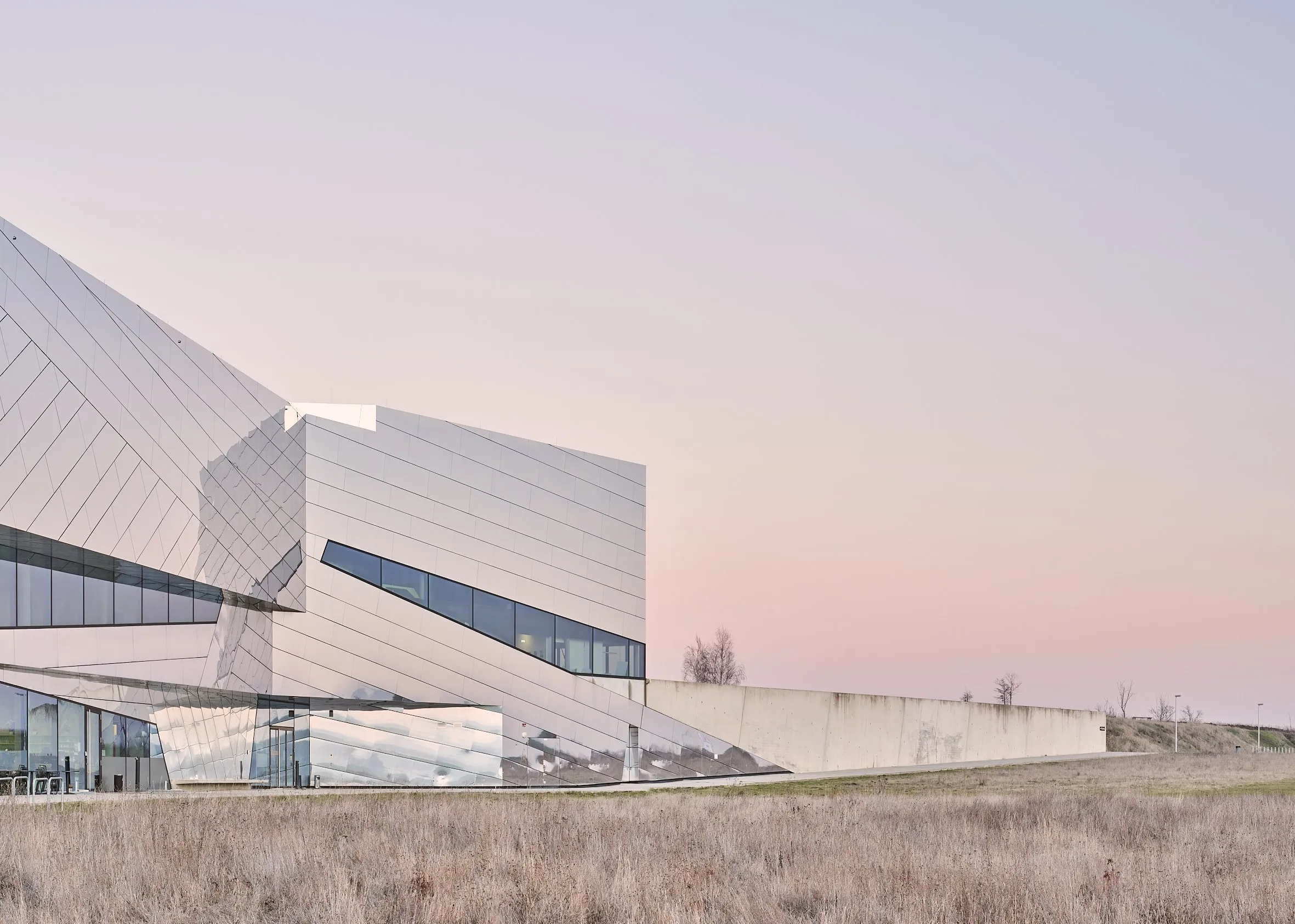 Das Paläon in Schöningen im Abendlicht, kristalliner weißer Baukörper mit gefalteter Aluminiumfassade über trockenem Magerrasen, Architektur von Holzer Kobler