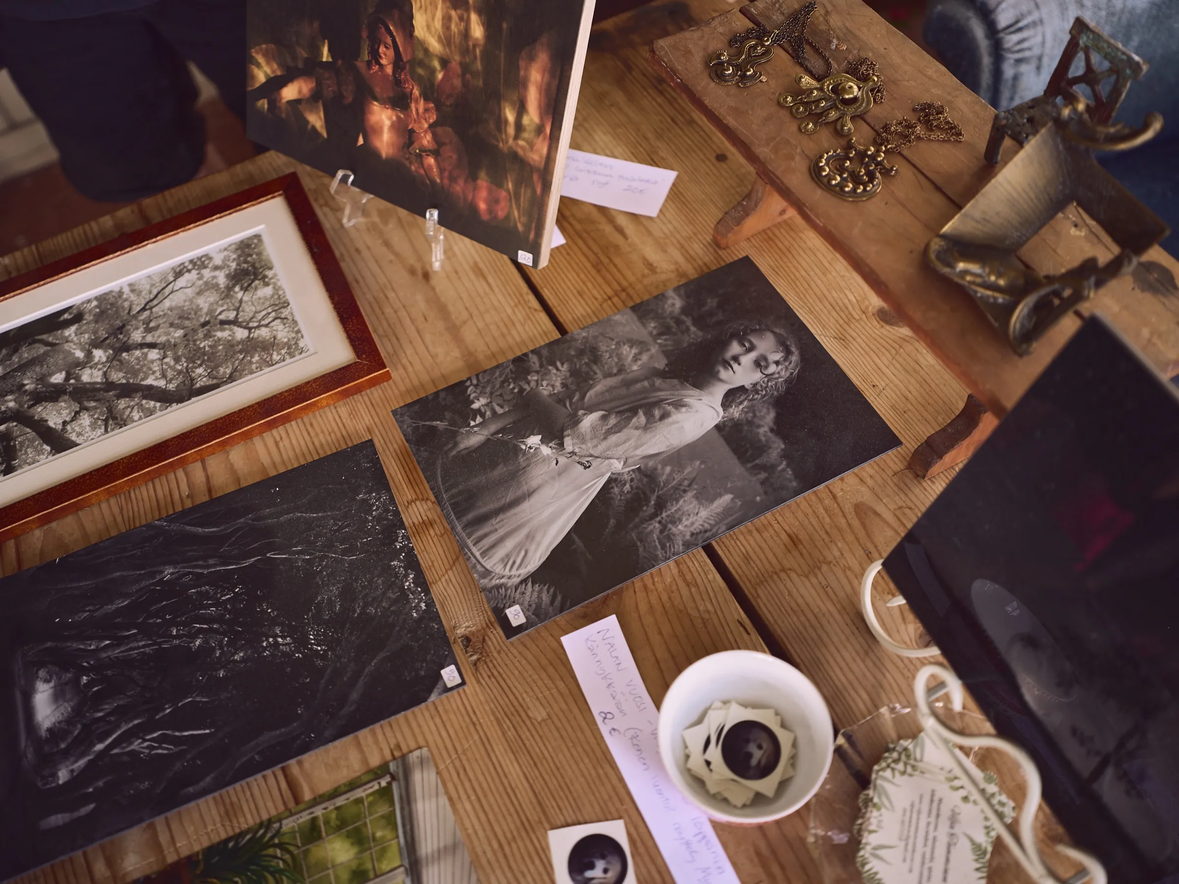 Tischplatte voller gerahmter Bilder und Grafiken, dazwischen eine Kaffeetasse