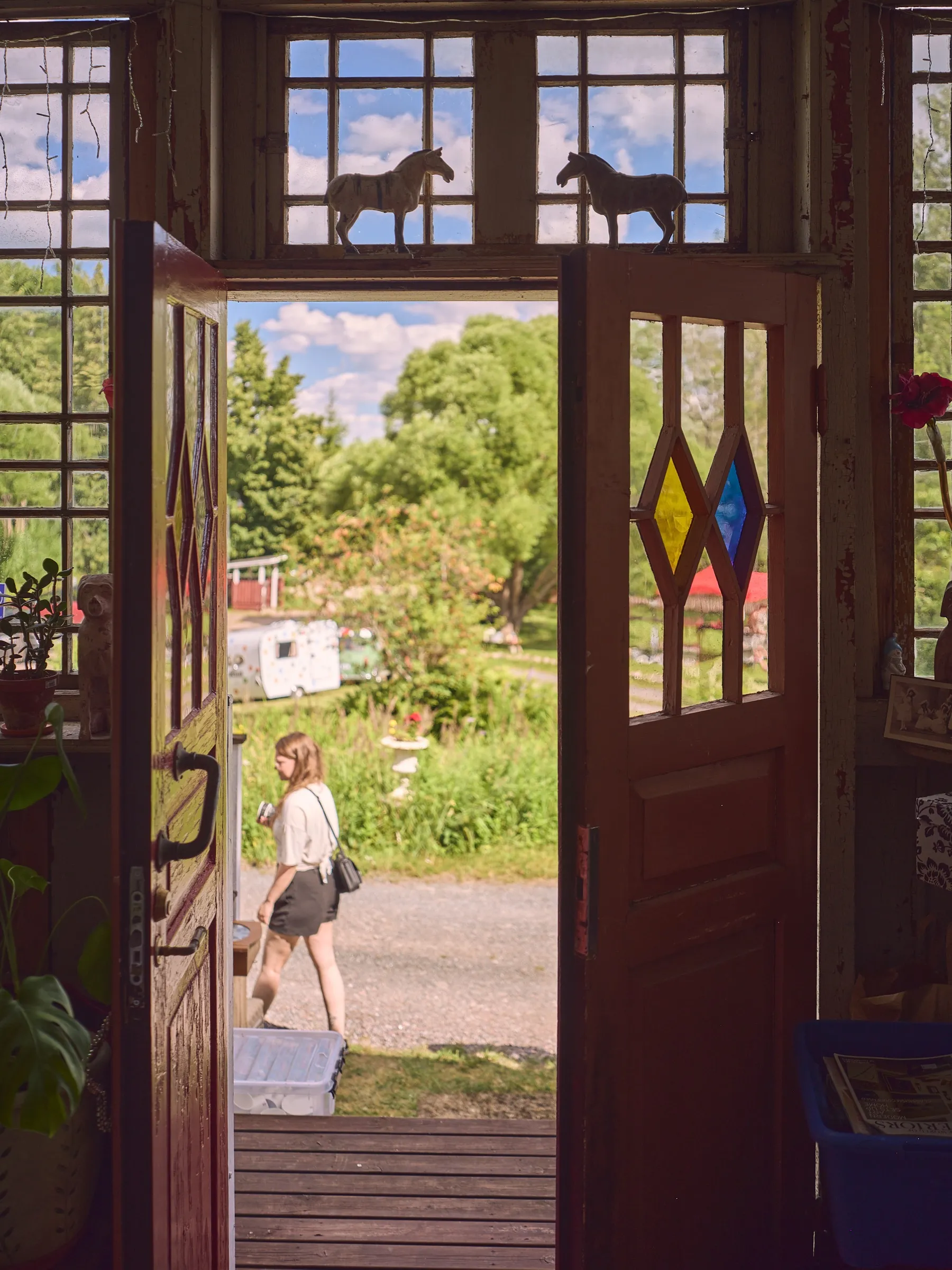 Geöffnete Flügeltür mit bunten Glasrauten, Blick hinaus auf den sommerlichen Hof, Hochformat