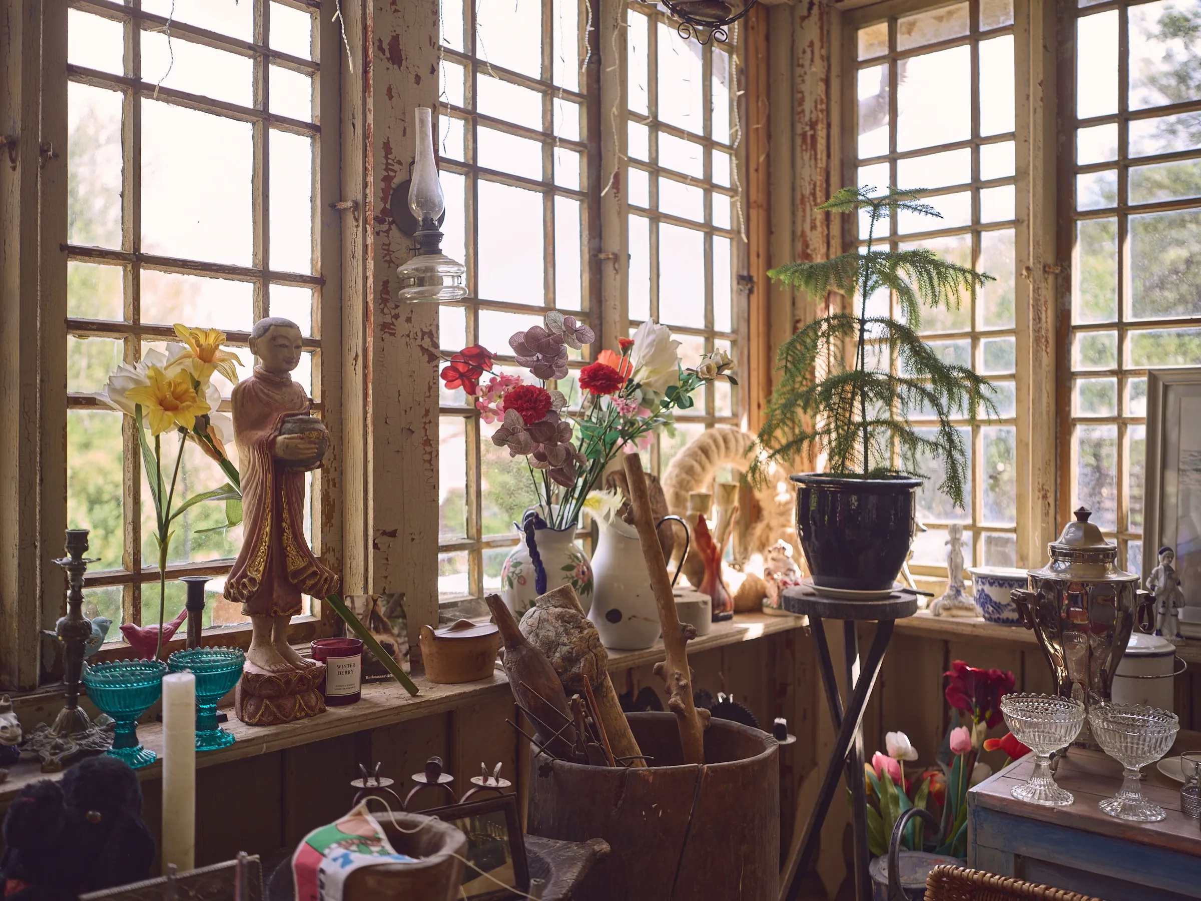 Fensterbank der Veranda mit Kunstblumen, Figuren und Vasen im Gegenlicht