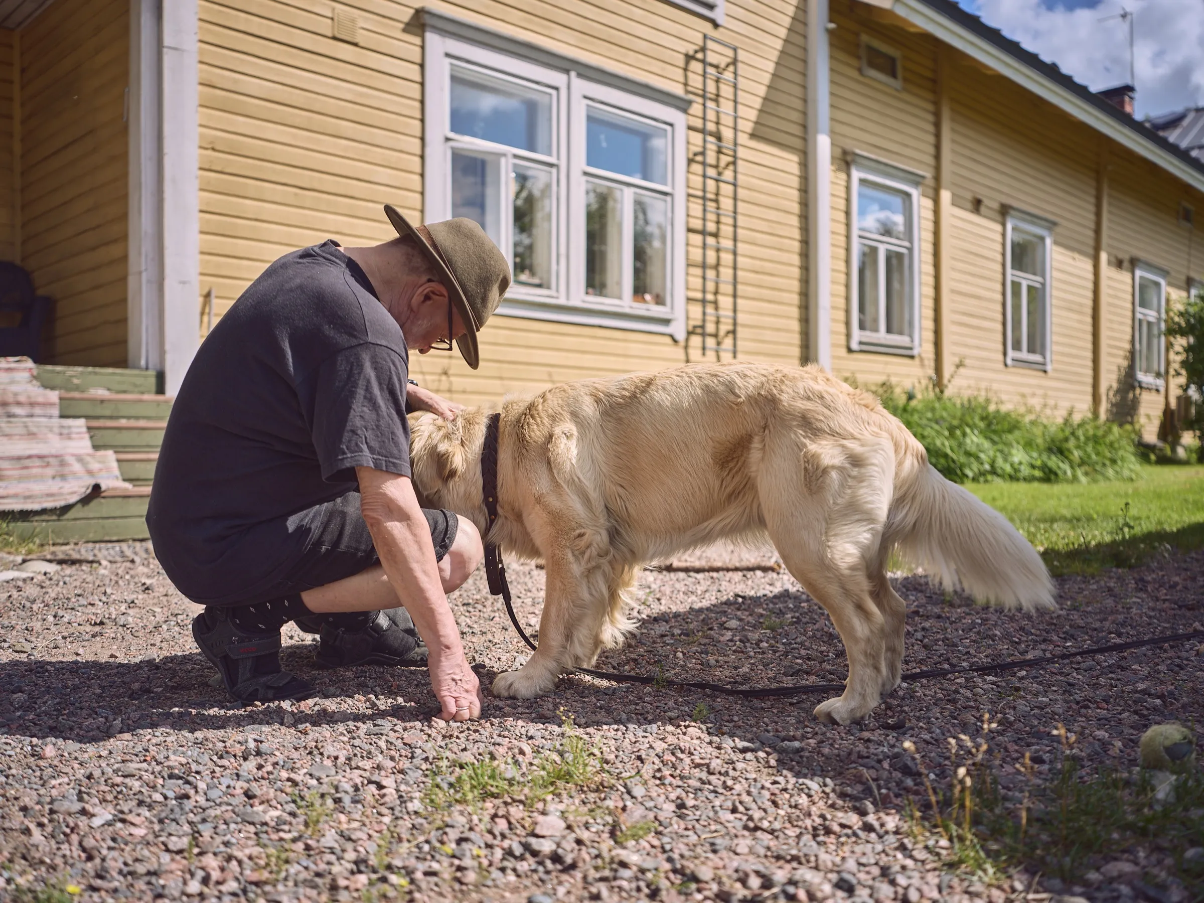 Terho hockt im Kies und begrüßt einen Golden Retriever