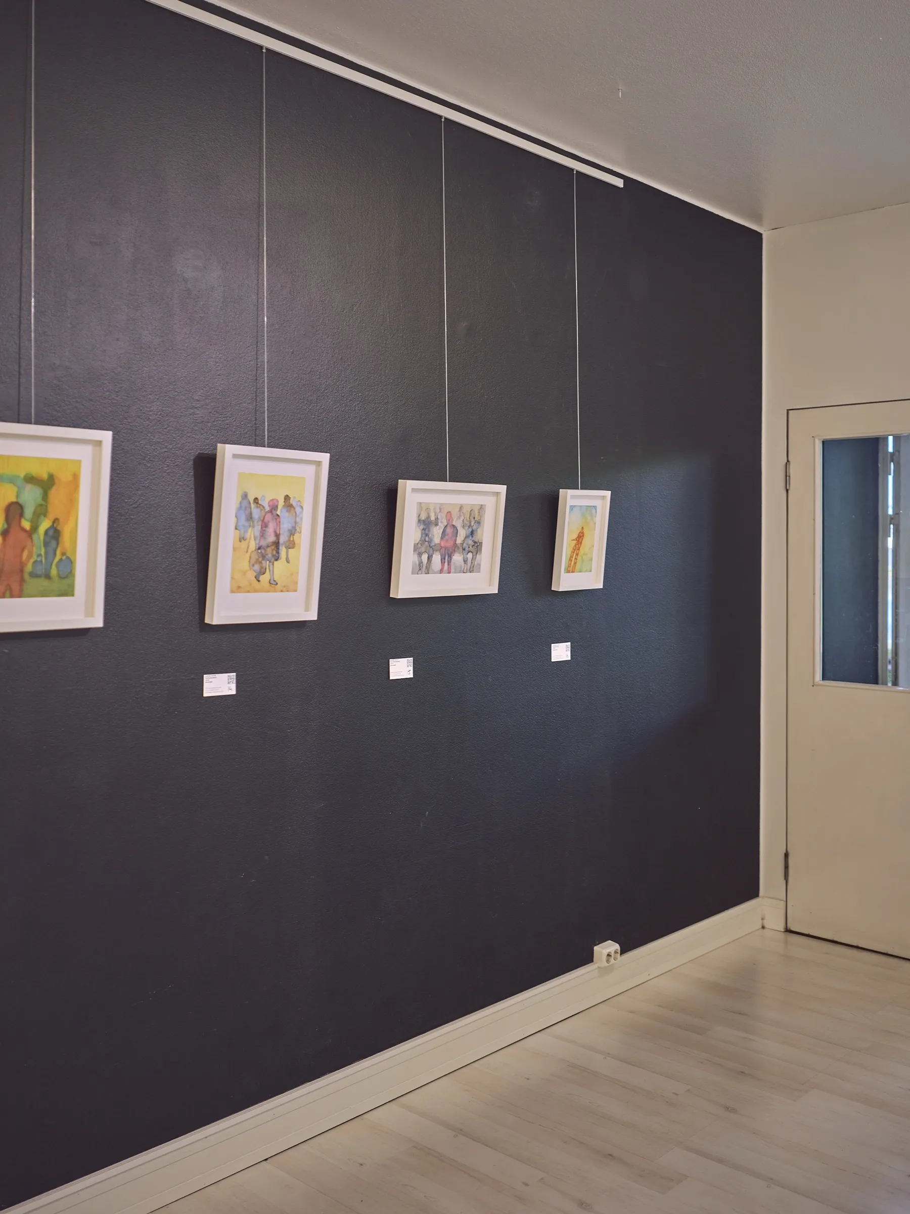 Dunkle Galeriewand mit vier kleinen, hell gerahmten Aquarellen, Hochformat