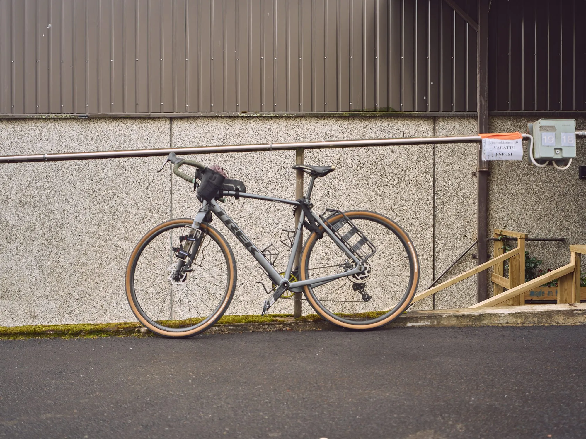 Ein Fahrrad lehnt an einer Betonwand vor der Galerie, menschenleere Sommerstraße
