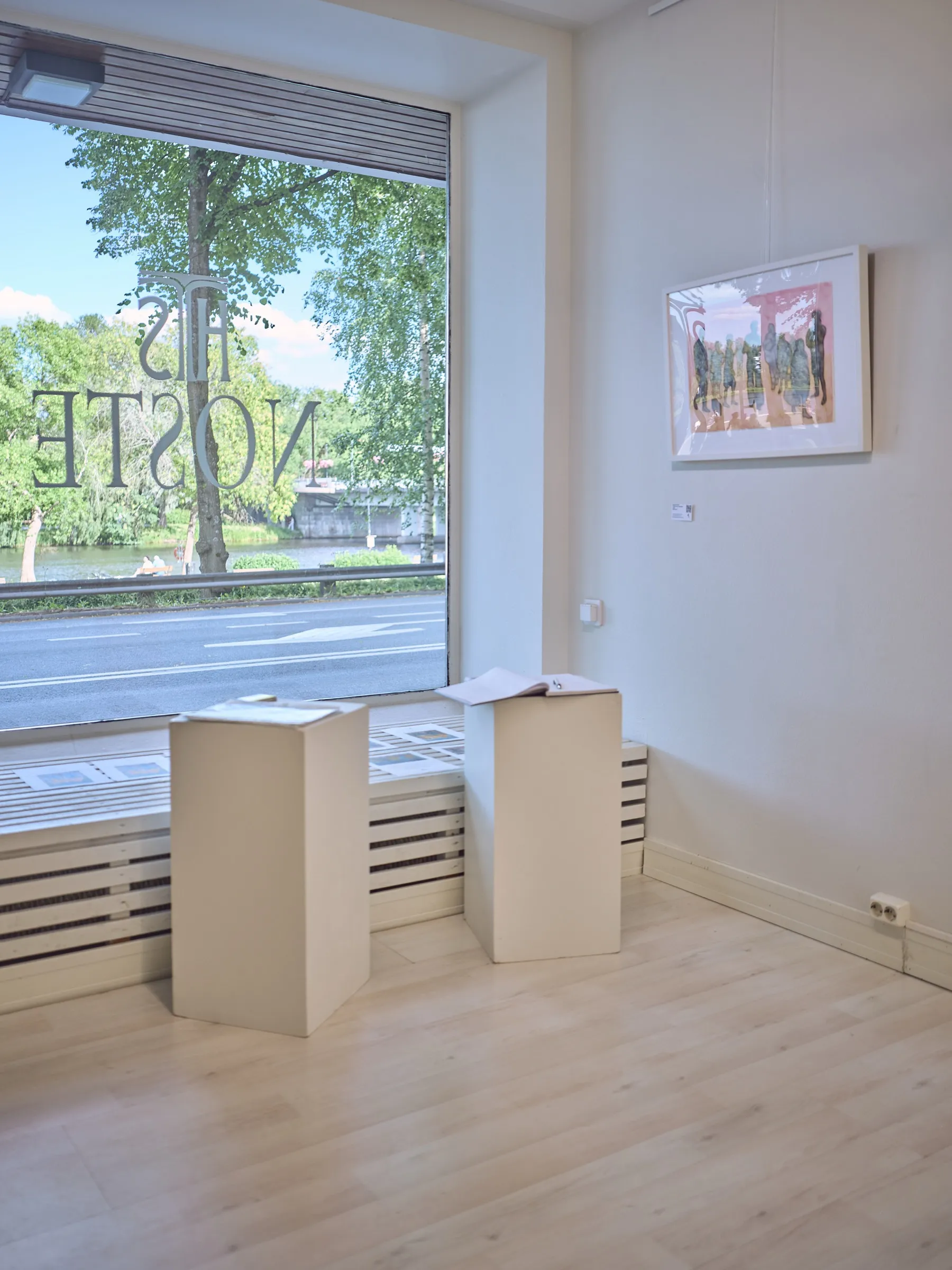 Zwei weiße Sockel vor dem Schaufenster der Galerie, draußen Straße und Bäume, Hochformat
