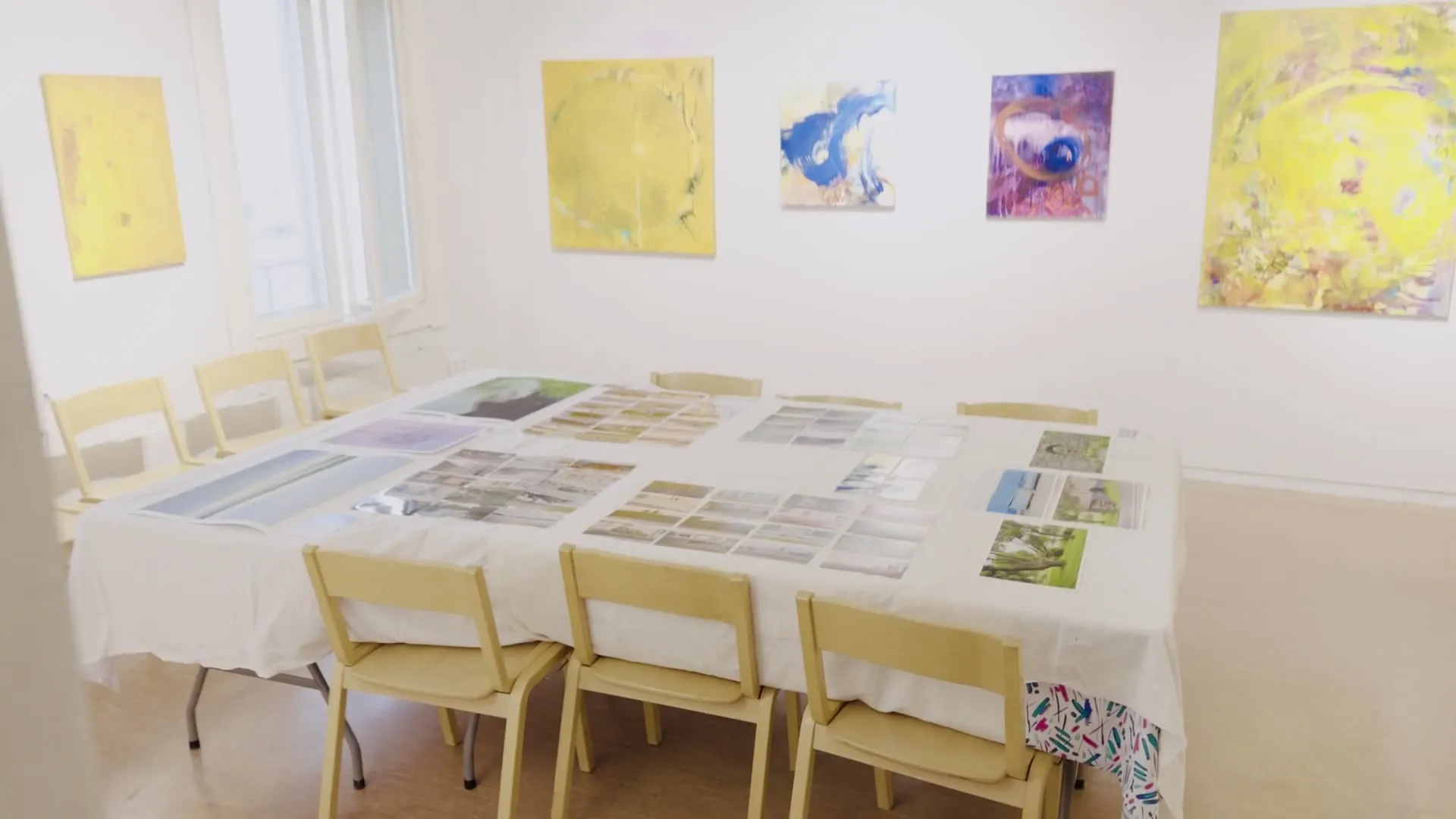 Video: Schwenk über den langen Tisch mit den ausgelegten Drucken im hellen Raum